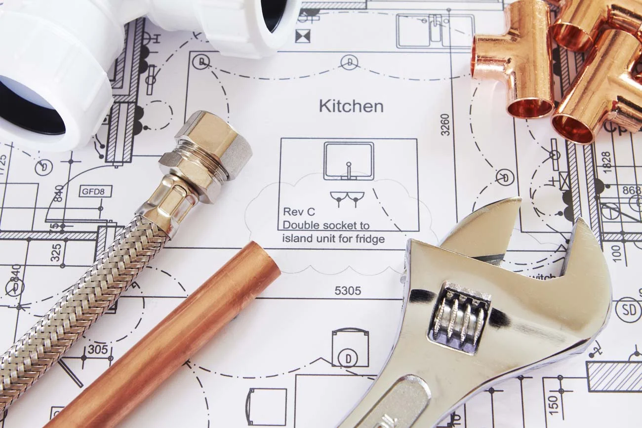 Plumbing pipework and fittings laid over a kitchen floor plan